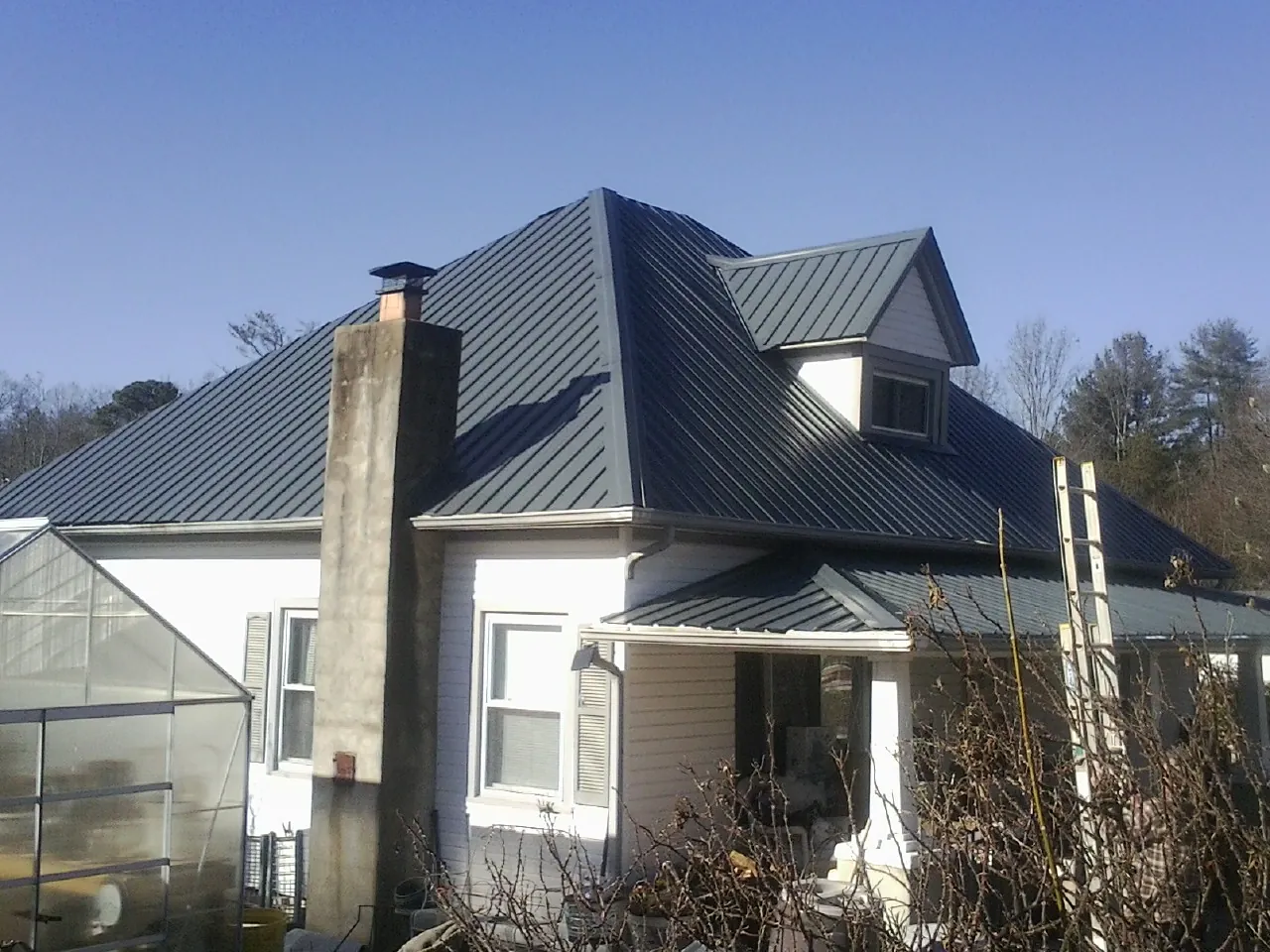 Dark blue standing seam metal roof on a white farmhouse with dormer — Slate & Tile Roof Repair by Roofing Brothers in Union City