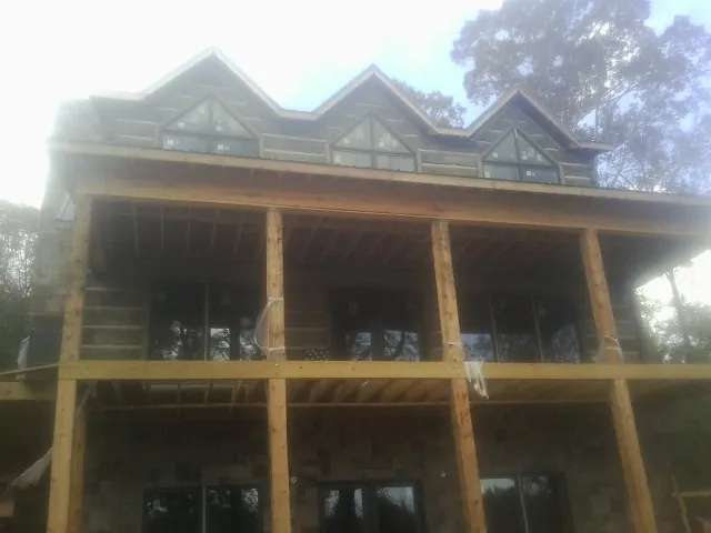 Dormers and porch framing on a large log home under construction — Roof Coating work by our crew in Union City
